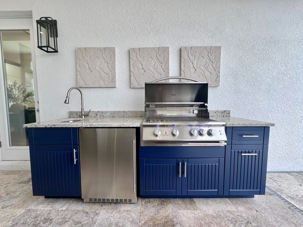 small blue outdoor kitchen with cabinets, grill, fridge, and sink 